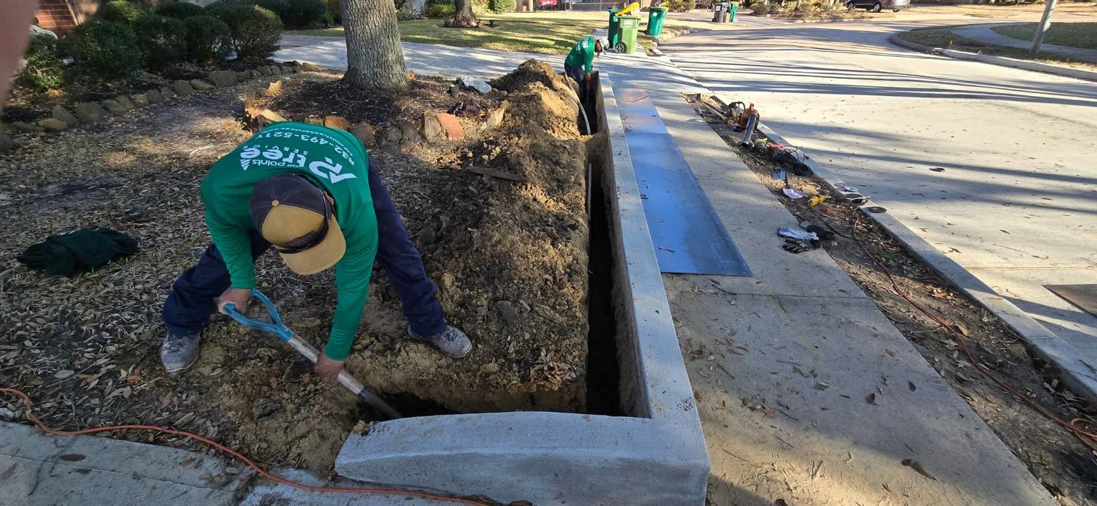 All Points Tree Service crew installing a root barrier beside a sidewalk